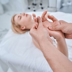 Blonde female patient lying on the couch during the acupressure treatment performed by a certified professional